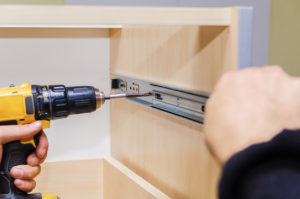Assembling furniture from chipboard, using a cordless screwdriver, close up.